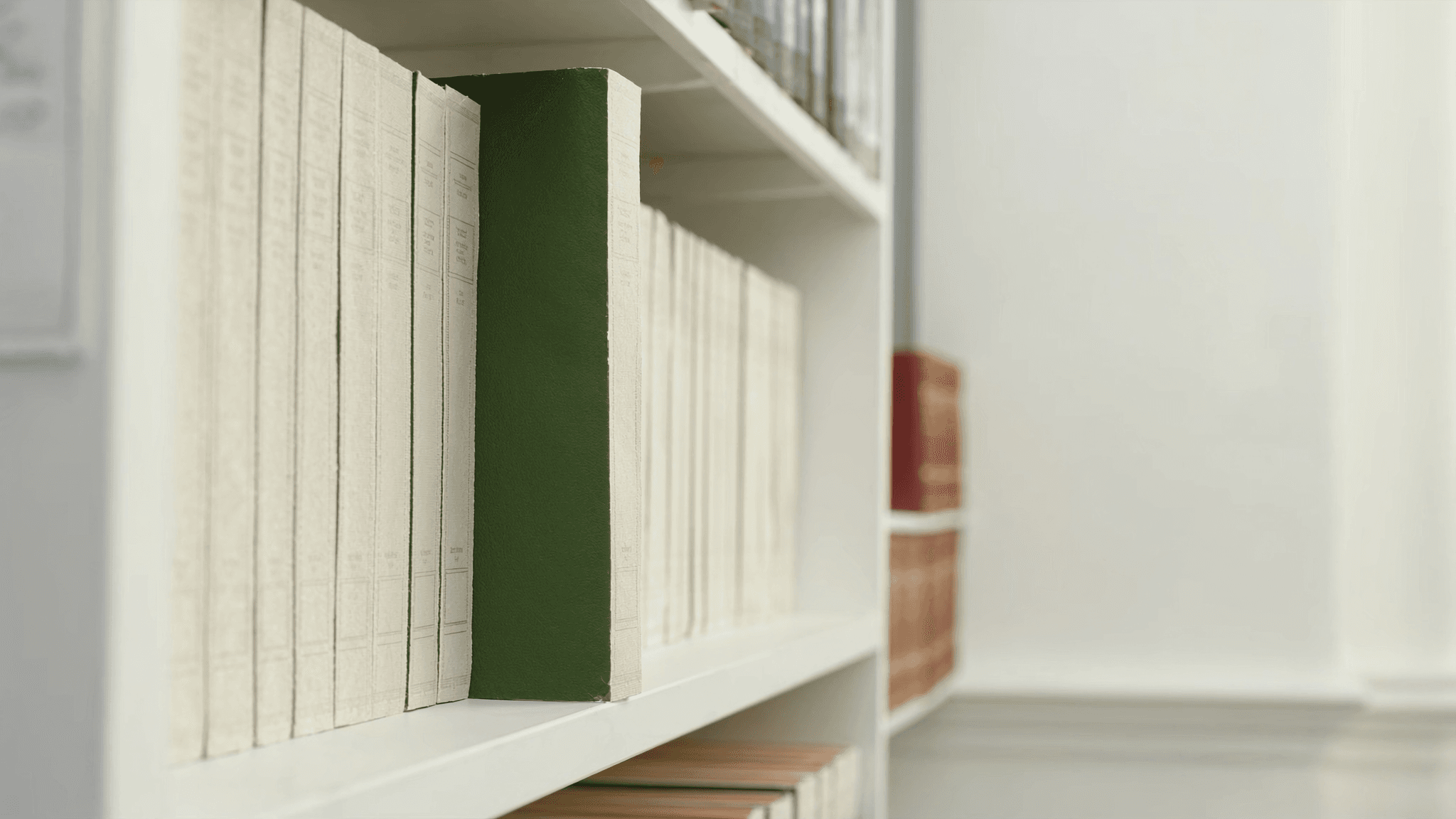 Archive shelf of pale-linen-bound technical manuals in a bright open library, a single emerald-leather spine reading vertically