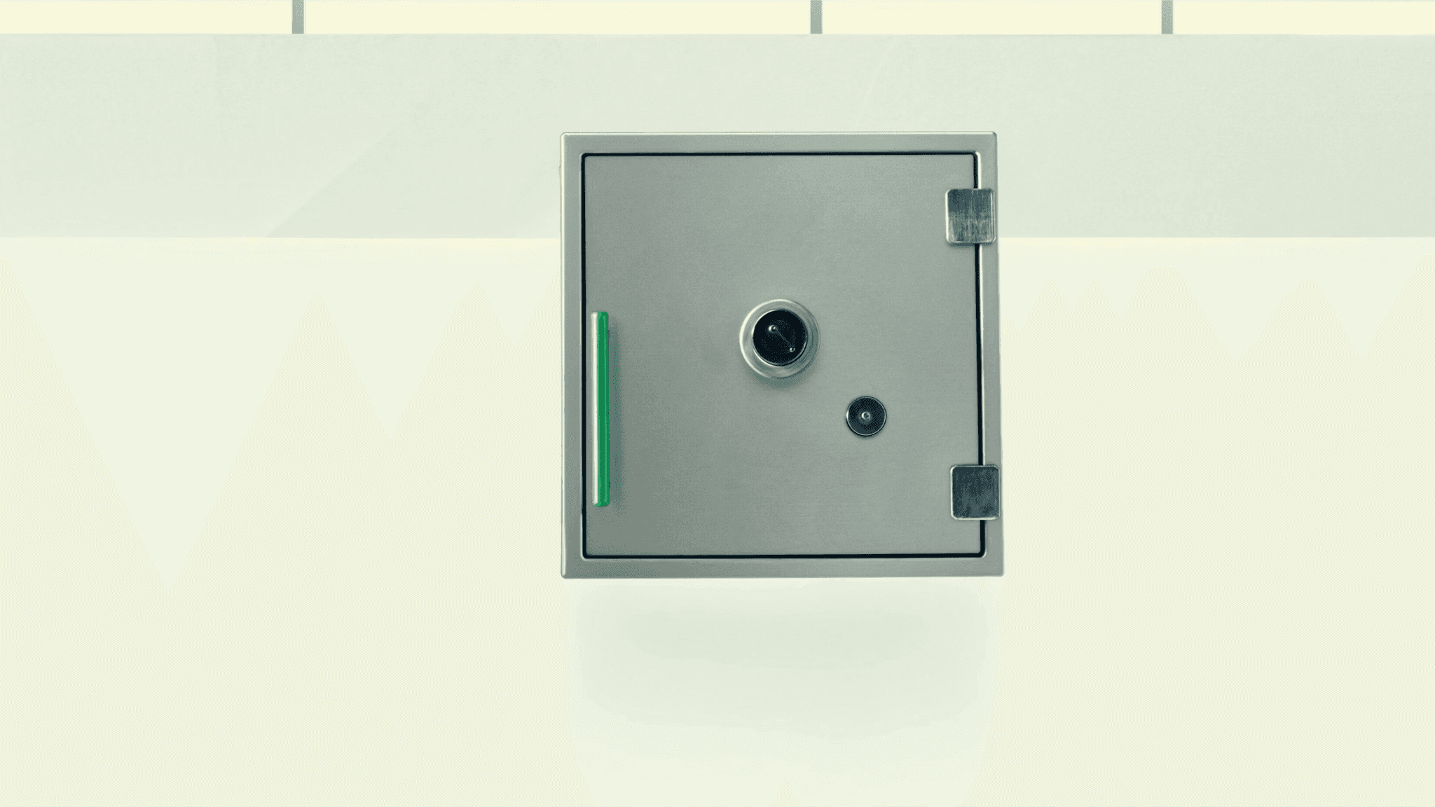 Pale brushed-steel vault-door form in a bright reception space, emerald-anodised handle as the focal accent, soft top-light