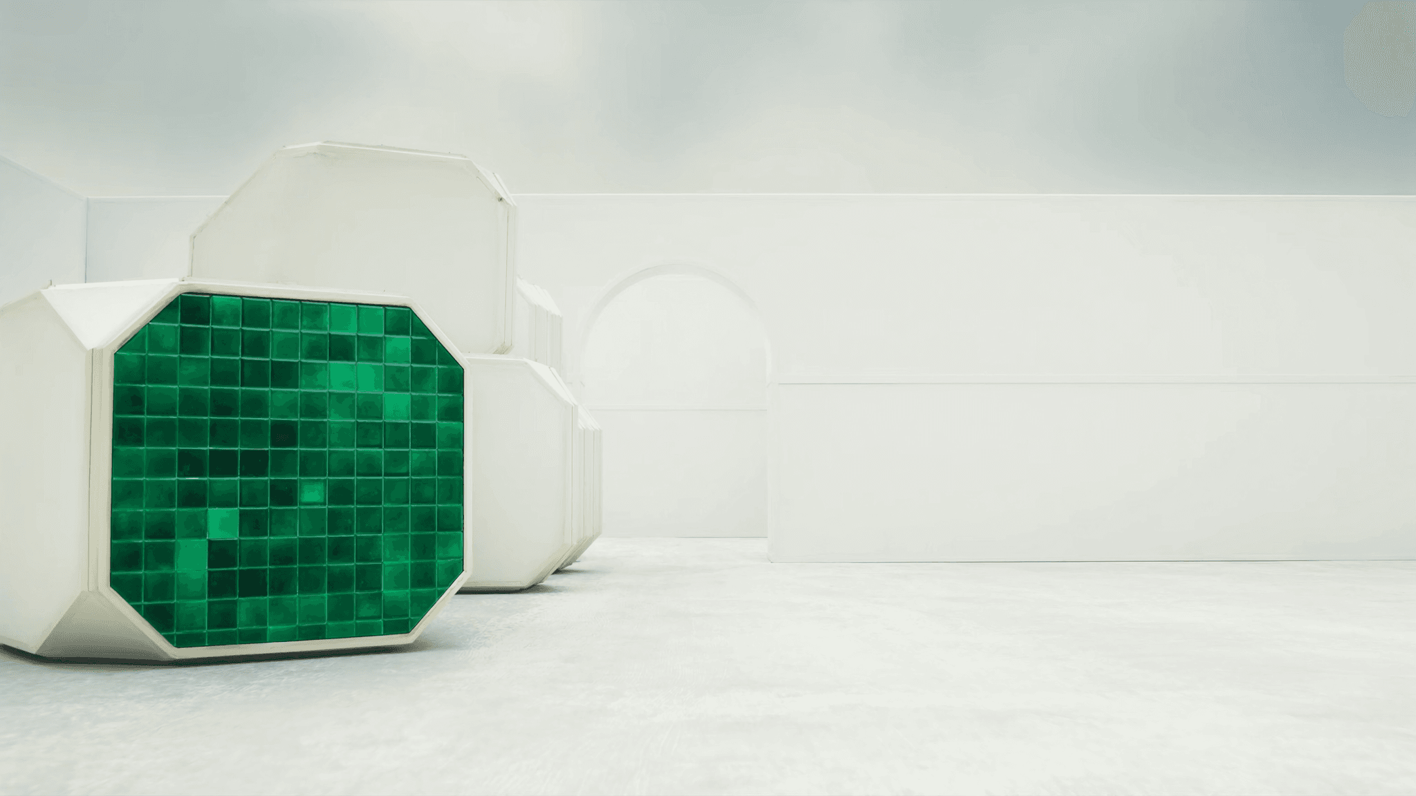 Cluster of modular hex units on a chalk-white production floor under overcast daylight, foreground unit clad with an emerald-glazed tile panel