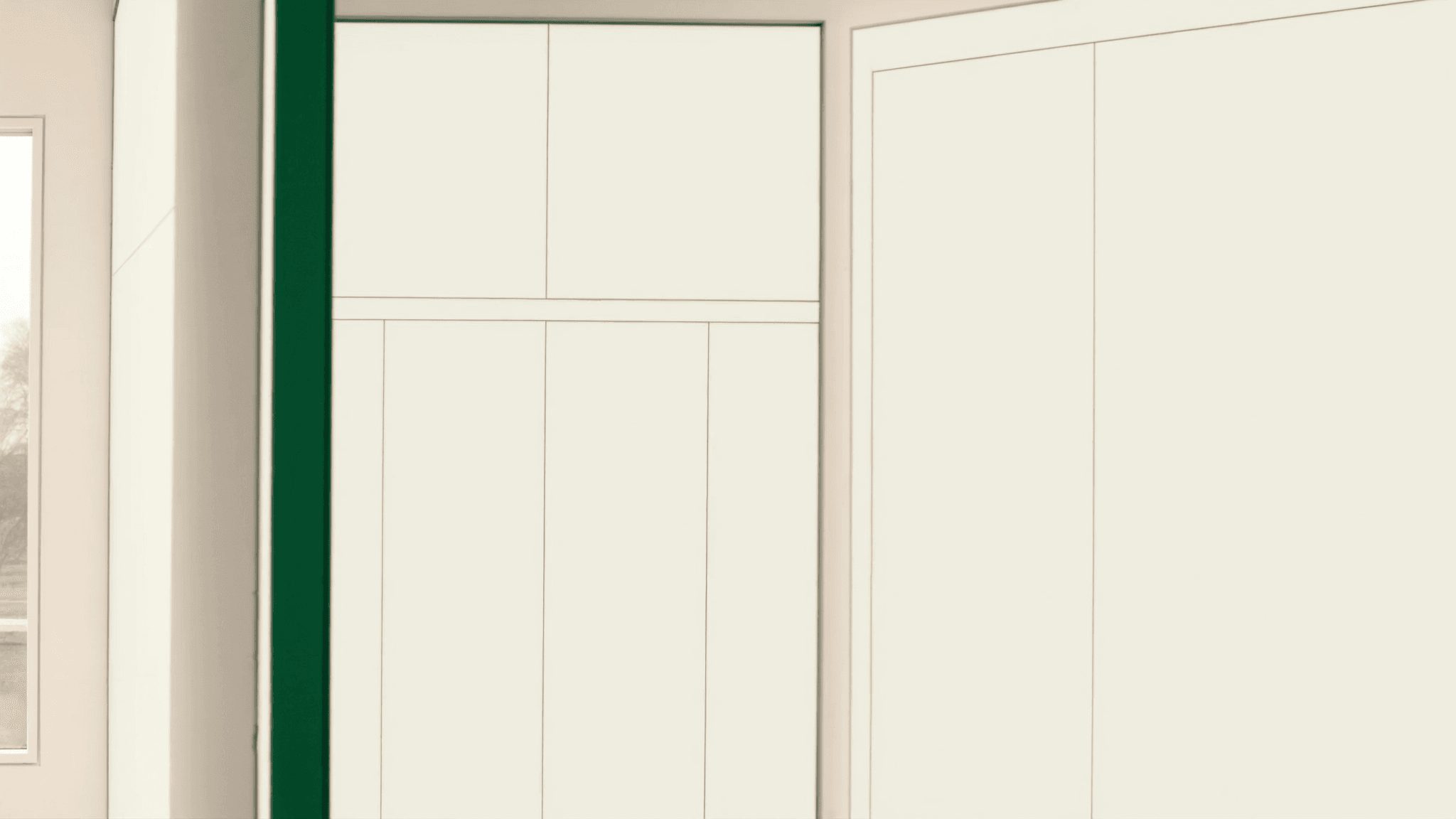 Open white-rendered doorway in a bright minimalist interior, emerald-painted door frame, morning sun beyond the threshold